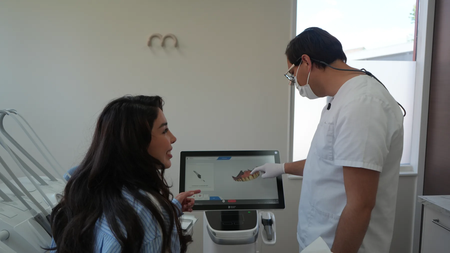 Patiënte en tandarts bekijken samen de 3D-scan van haar gebit op het scherm.