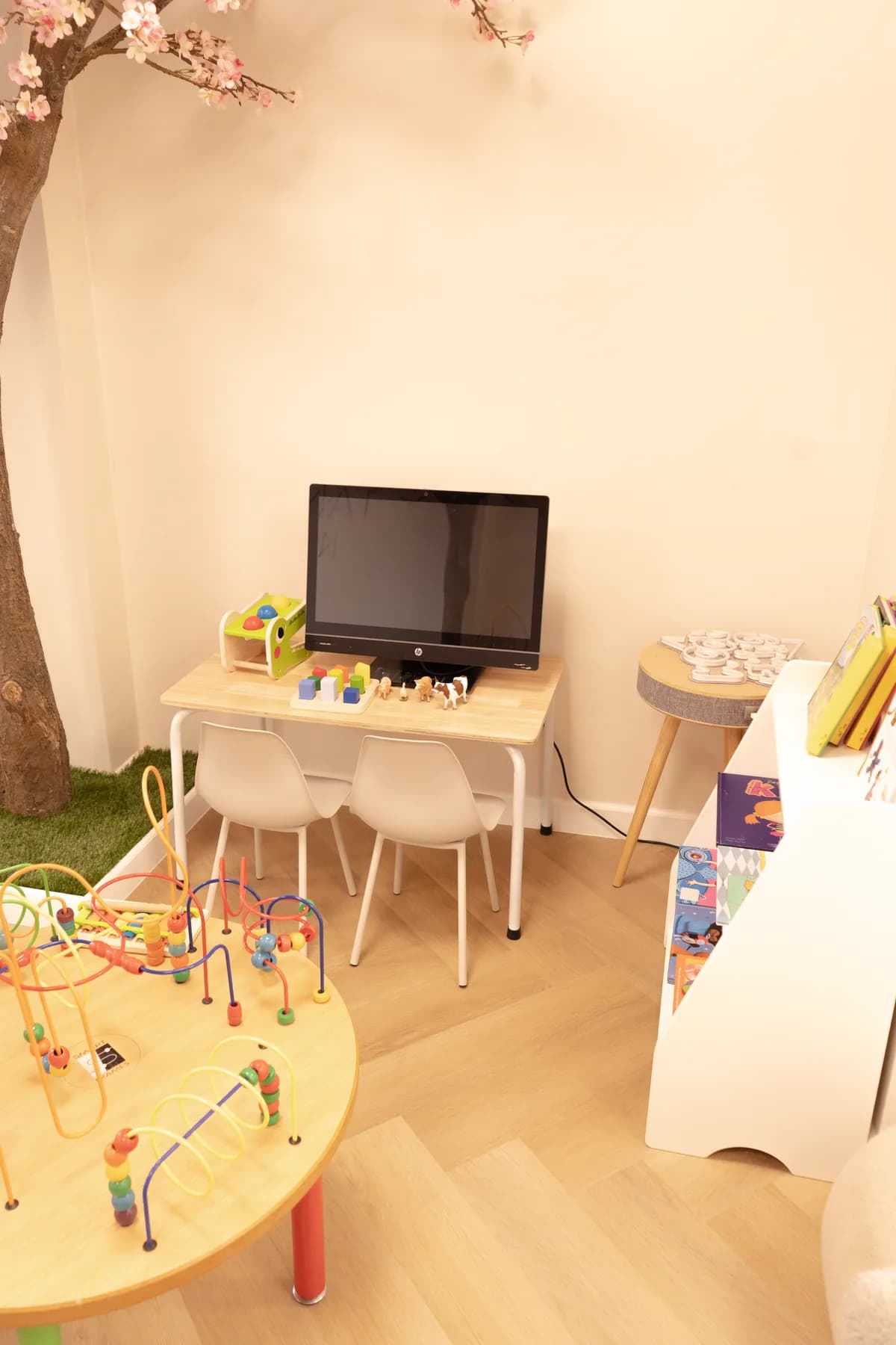 Kinderhoek in de wachtkamer met speeltafel, kleine stoeltjes en boekjes.